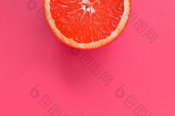 粉红色明亮背景上一片葡萄柚的俯视图。饱和柑橘纹理图像