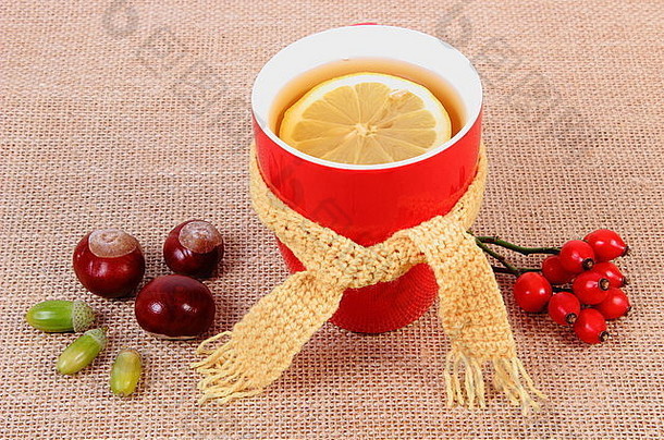 一杯热茶，配柠檬皮羊毛围巾和秋季装饰，为流感和感冒提供温热饮料