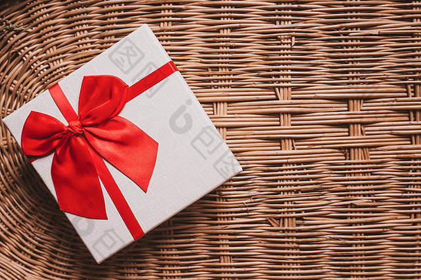 礼品白色盒子配红色缎带编织竹木背景舒适温馨的家居欢迎概念理念
