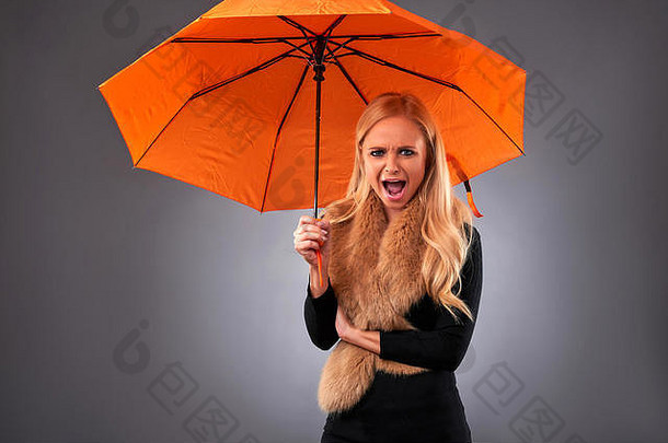 一个漂亮的年轻女子戴着雨伞尖叫着