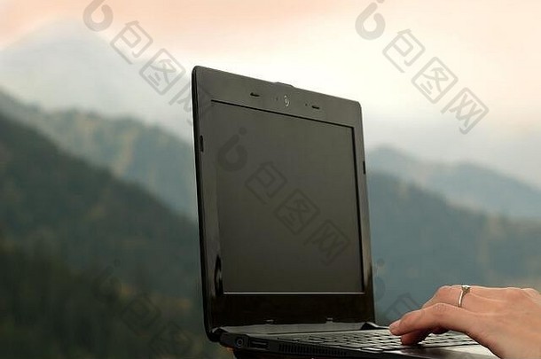 在山的背景下有一个空白的<strong>黑色桌面</strong>的笔记本电脑。自由职业者的概念