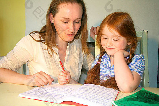 一位母亲坐在她的孩子旁边，看着她的家庭作业