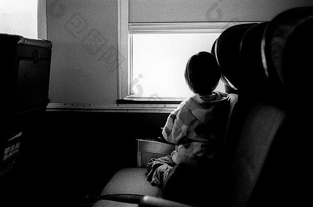 小孩跪在<strong>火车</strong>座位上向窗外看。