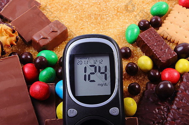 血糖仪，一堆糖果，饼干和红甘蔗糖，太多<strong>的</strong>糖果，不健康<strong>的</strong>食物，<strong>糖尿病的</strong>概念和减少
