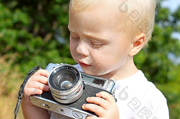 可爱的婴儿男孩坐着秋天一天玩古董相机