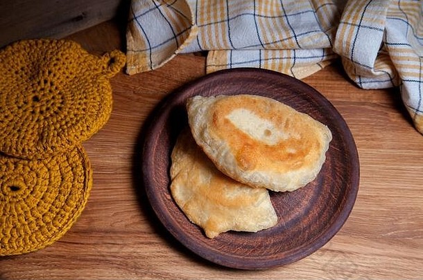 木桌上放着两个单独的带肉的油炸馅饼。鞑靼传统派。