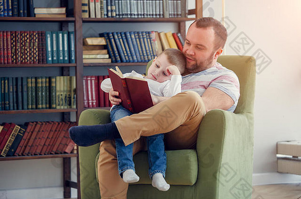 爸爸给坐在椅子上的儿子看书的照片