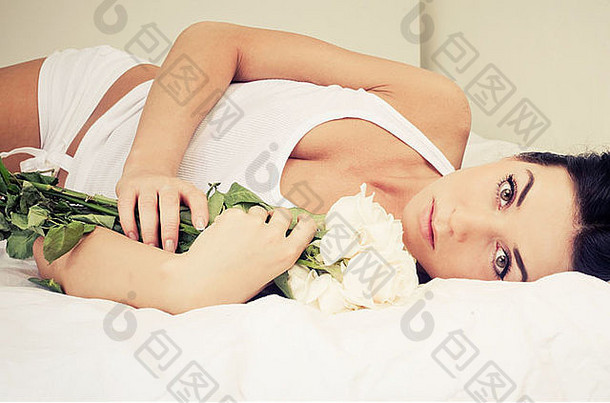 美丽的年轻的女人玫瑰床上首页