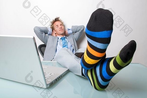 昏昏欲睡的商人把袜子放在笔记本电脑旁边的桌子上休息