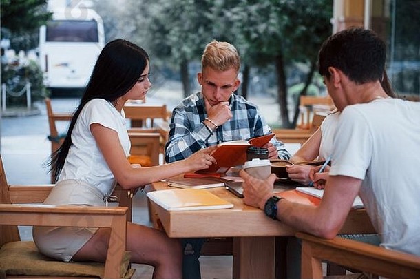 坐在咖啡馆里聊天。四个穿着休闲服的年轻学生在雨天开会