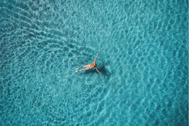 蓝色泻湖中<strong>游泳</strong>女子的鸟瞰图。土耳其奥卢德尼兹的地中海。<strong>夏日</strong>的海景，碧蓝的海水，日出时的波浪。T