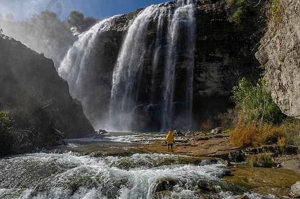 冒险者在土耳其看托尔图姆瀑布。穿着黄色夹克的游客在土耳其的托尔图姆瀑布放松。托尔图姆景观