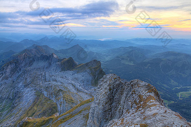 瑞士，在薄雾的距离和日落时的绿色草地上，阿尔卑斯<strong>山参</strong>差不齐的尖锐喀斯特山顶山脉摇摇欲坠