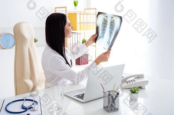 美丽医生的照片放射科医生的女士看学习看人类骨骼肺x光片对面浅色穿白色实验室外套衬衫坐在椅子上