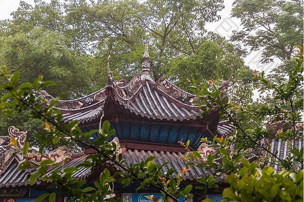 中国丰都——2010年5月8日：鬼城，历史圣地。绿色树叶下的棕色中国建筑屋顶结构特写。一些蓝色的，gre