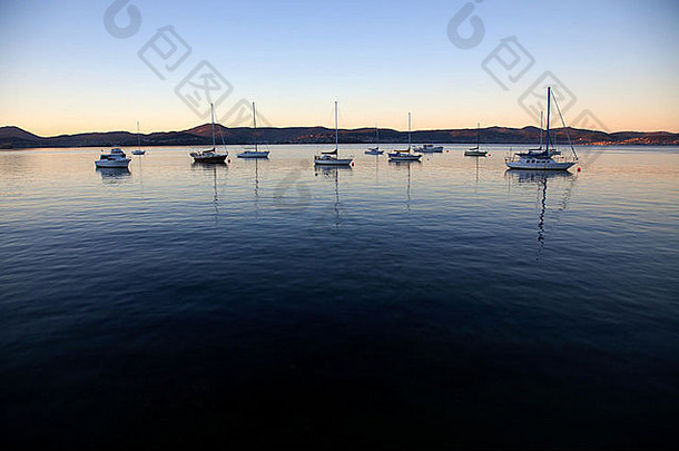 黄昏时分，<strong>澳大利亚塔斯</strong>马尼亚州霍巴特，河流上的帆船剪影，背景是山