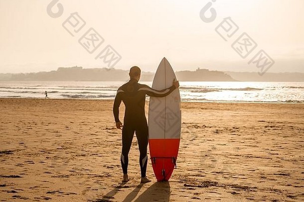 后视图运动员冲浪者冲浪板海滩日落日出轮廓冲浪男人。海洋等待高波极端的