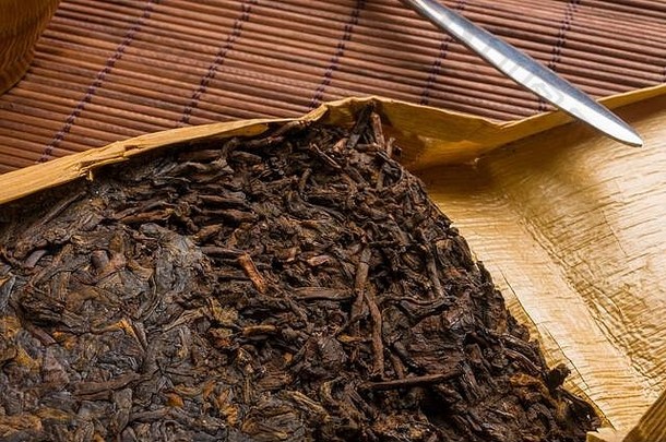 竹叶包装的中国普洱茶和竹席上的茶刀，特写