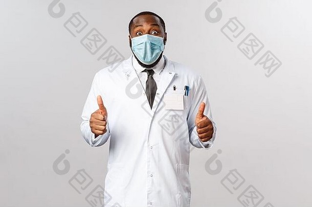 穿着白大褂的快乐、兴奋的非洲裔美国男医生的肖像，推荐令人敬畏的药物或诊所服务，高兴地竖起大拇指