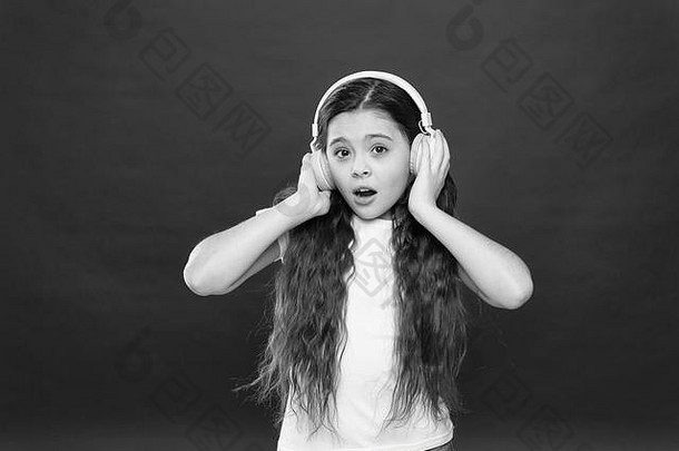 音乐在青少年的生活中起着重要的作用。音乐对青少年的情感、感知世界有着强大的影响。女孩戴着红色背景的耳机听音乐。现代小工具概念。音乐品味。
