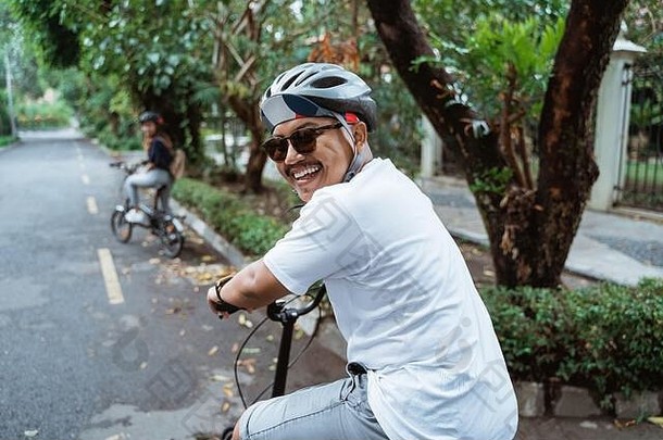 亚洲年轻人在路上骑<strong>自行车</strong>时回首往事，微笑着