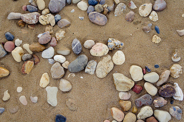 美丽的海滩沙滩背景和鹅卵石。褐色砂质结构，含石块。夏季概念。顶视图。