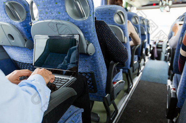 旅游巴士上带着智能手机和笔记本电脑的男子