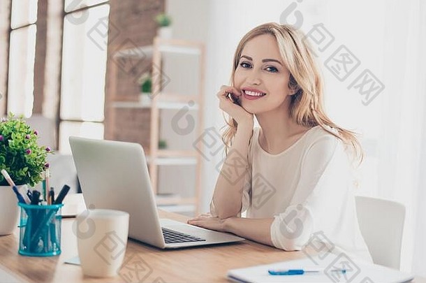 坐在桌子旁用电脑工作的快乐漂亮可爱的女人