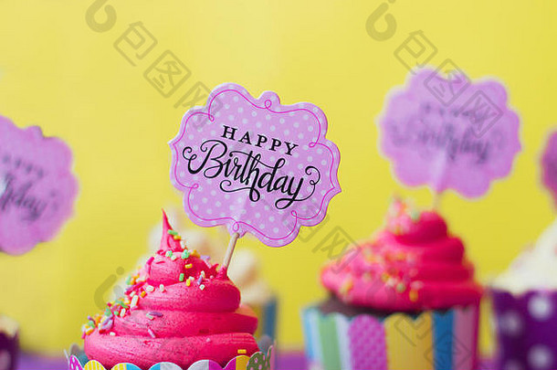黄色背景上印有生日快乐贺卡的美味草莓纸杯蛋糕。政党背景