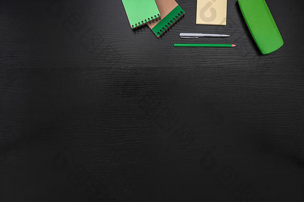 绿色、黑色、黄色办公桌商务背景，配有便利贴、精美的箱子、记事本、铅笔和钢笔
