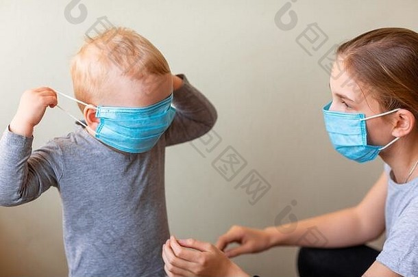一个十几岁的女孩帮助他的小弟弟戴上医用口罩。冠状病毒防护，戴口罩概念