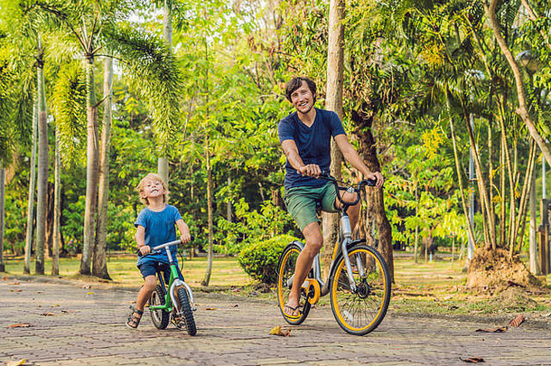 快乐家庭骑自行车在户外微笑父亲自行车儿子balancebike
