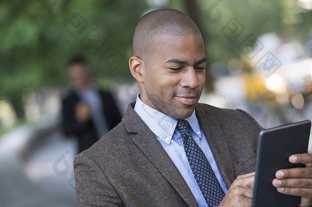 两名男子在公园里走动，一人使用数字平板电脑，一人检查智能手机