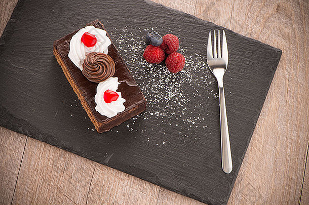 一块巧克力蛋糕浆果黑暗板岩托盘