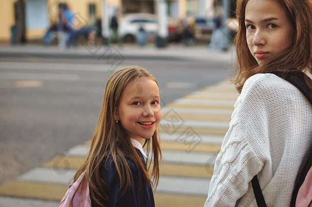 两个可爱的少女在城市街上。女孩们站在高速公路的人行横道附近。<strong>交通法规</strong>。