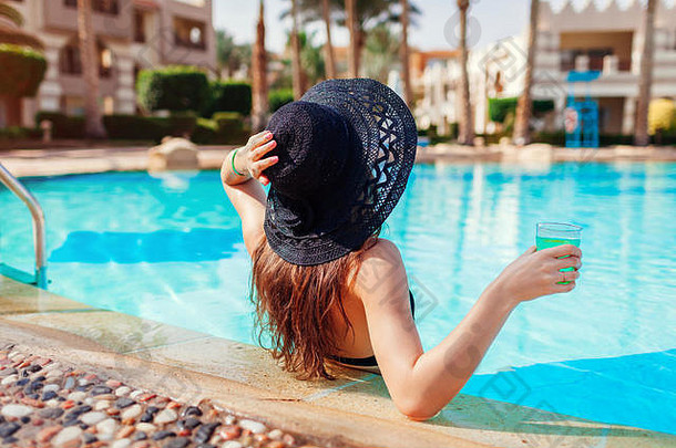 一位女士在酒店的游泳池里拿着一杯鸡尾酒。<strong>暑假</strong>一<strong>价</strong>全包