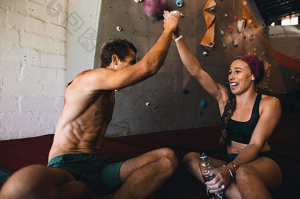 成功完成攀岩后，男女攀岩运动员击掌击掌。快乐的攀岩情侣在工作后放松。
