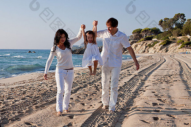 夏日生活方式中带着女儿在海滩上的快乐年轻家庭