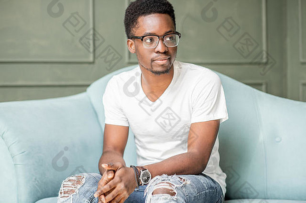 一位非洲裔年轻男子在办公室与心理学家进行心理咨询时坐在<strong>沙发</strong>上的画像