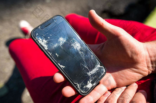 破碎的损坏的智能手机裂缝玻璃屏幕年轻的男人。失望伤心持有电话手概念愤怒愤怒# x1f60a