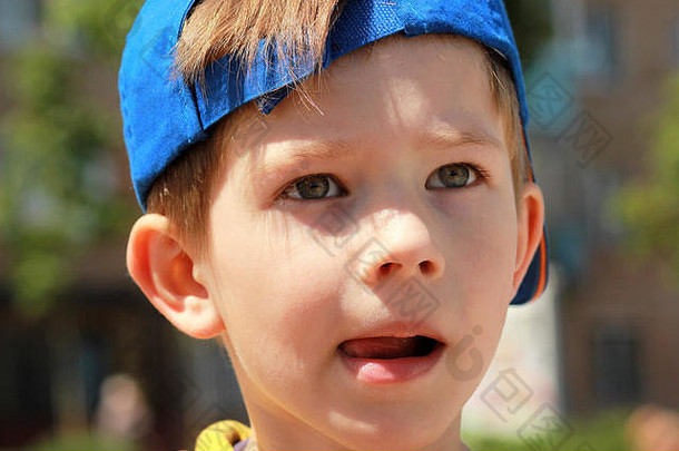 关闭肖像男孩脸表达式穿蓝色的棒球帽