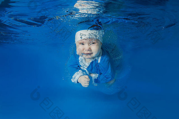 穿着圣诞老人蓝色套装的小女孩在游泳池里游泳