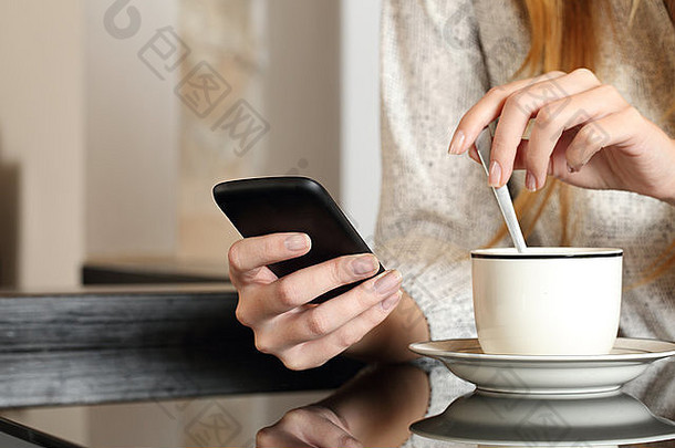 在家里准备咖啡杯时，一位女士在早餐时用智能<strong>手机</strong>
