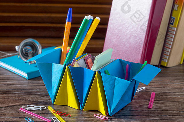 一个由纸制成的儿童办公室组织者，里面装满了办公用品。手工制作的。儿童创意项目，手工折纸。