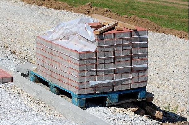 木托盘部分堆放灰色红色的矩形石头瓷砖覆盖尼龙保护左砾石人行道上