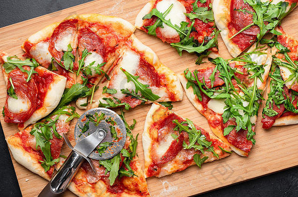 比萨配意大利腊肠、意大利干酪和番茄酱，配芝麻菜。切片披萨。桌面视图