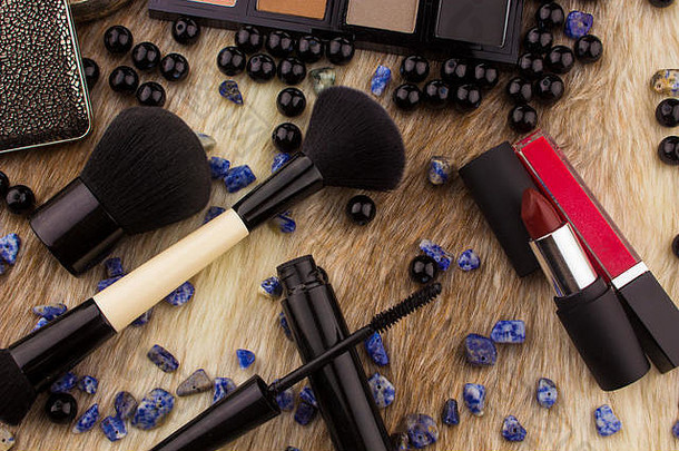 皮毛背景化妆工具，在愤怒的背景下有眼影调色板、唇膏、化妆刷