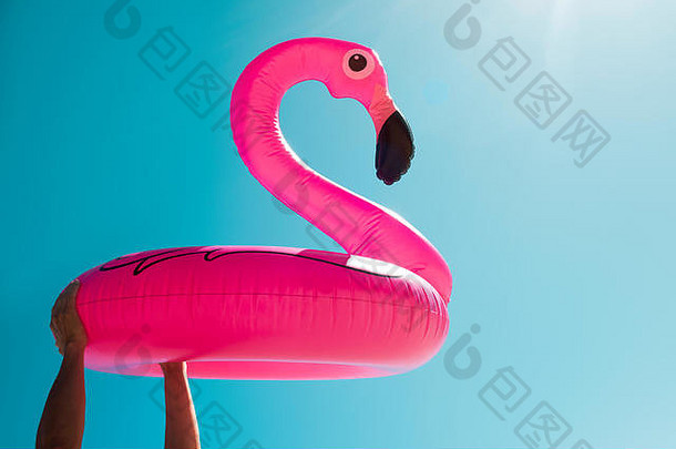 特写镜头年轻的高加索人男人。海滩游泳环形状粉红色的火烈鸟手蓝色的天空空白间距