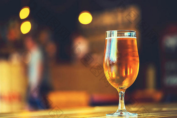 啤酒节的美丽背景。酒吧的木制吧台上放着一杯冰镇新鲜的淡啤酒，为您的客人提供免费空间