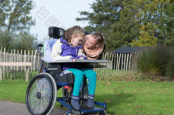 一名<strong>残疾儿童</strong>坐在轮椅上，与一名志愿护理人员在室外休息